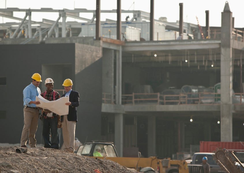 Team of contractors discussing architectural plans at an active construction site