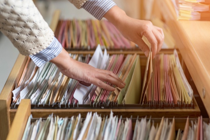 Person retrieving a file from a well-organized filing cabinet in an office setting