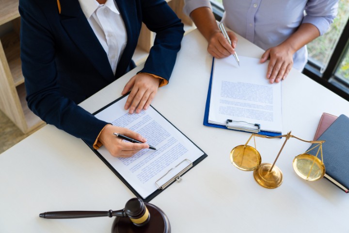 Legal consultation with two people going over documents, accompanied by symbolic legal items like a gavel and scales