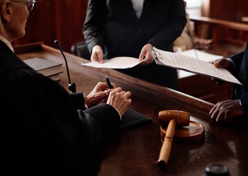 Judge reviewing documents presented by lawyers during a courtroom proceeding with a gavel placed on the desk