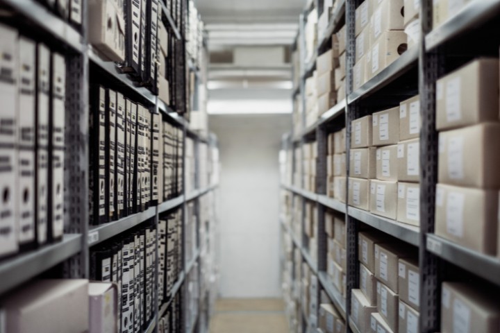 An organized storage room featuring file boxes and binders on metal shelving units