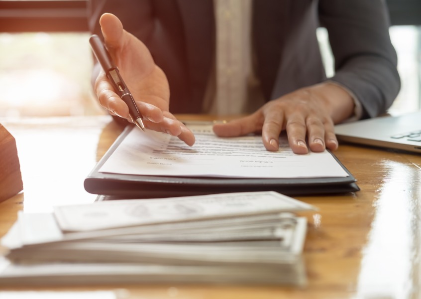 Close-up of a businessperson reviewing and signing legal documents related to payment and performance bonds in construction