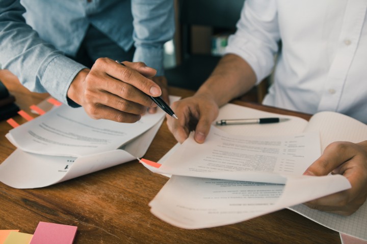 Close-up of bond specialists reviewing contract documents for surety bonds