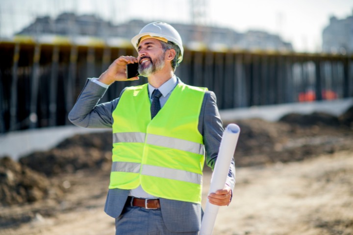 Contractor on the phone at a construction site after securing a project with a bid bond