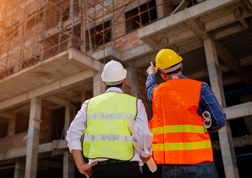 Contractor and surety bond specialist in safety gear discussing commercial bond requirements at a construction site in Houston