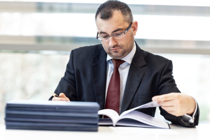 Surety professional in a suit reviewing documents related to bid bond claims.