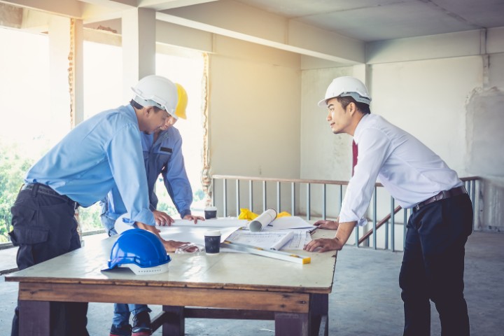 A construction industry surety consultant and contractor reviewing paperwork on-site to assess surety bond requirements