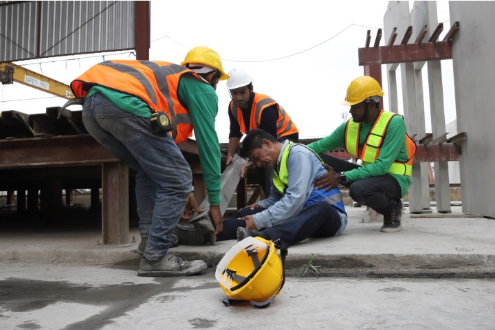 Workers assisting an injured colleague at a construction site