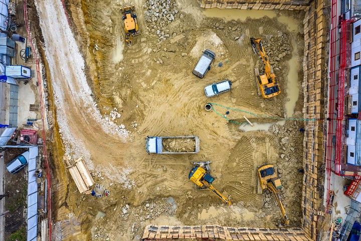 Aerial view of a construction site with machinery and vehicles symbolizing compliance and bond guarantees