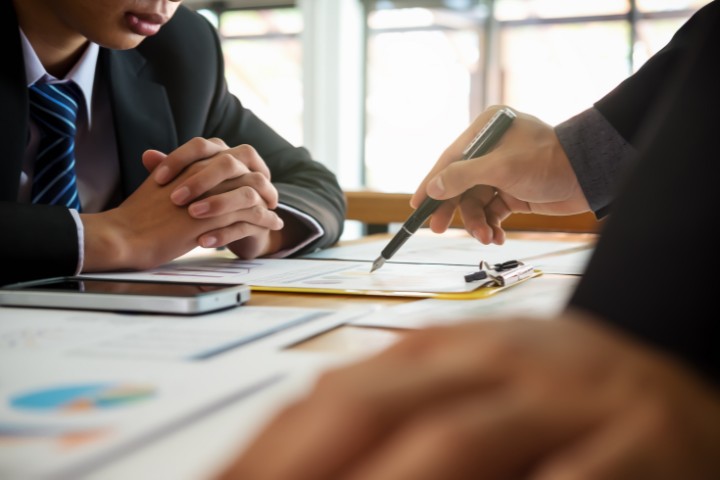 Close-up of a surety consultant and client examining documents to finalize surety bond agreements